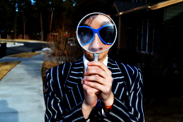 Homme tenant une loupe devant son visage